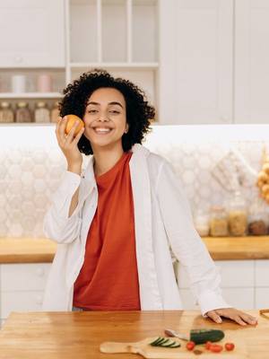 Fröhliche Frau mit Orange in der Küche